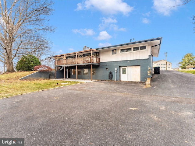 back of house featuring a lawn and a wooden deck