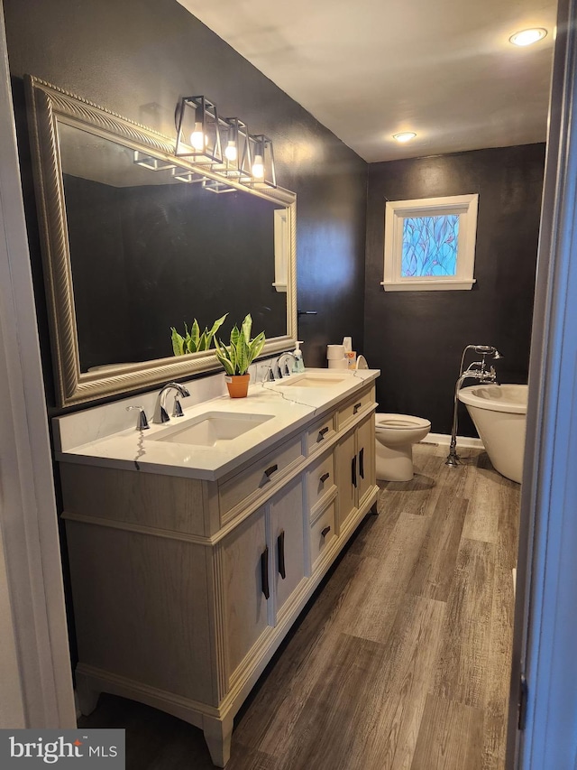 bathroom with vanity, a bathtub, toilet, and wood-type flooring