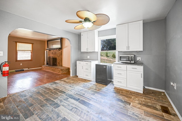 kitchen featuring a brick fireplace, dark hardwood / wood-style floors, white cabinetry, and a healthy amount of sunlight