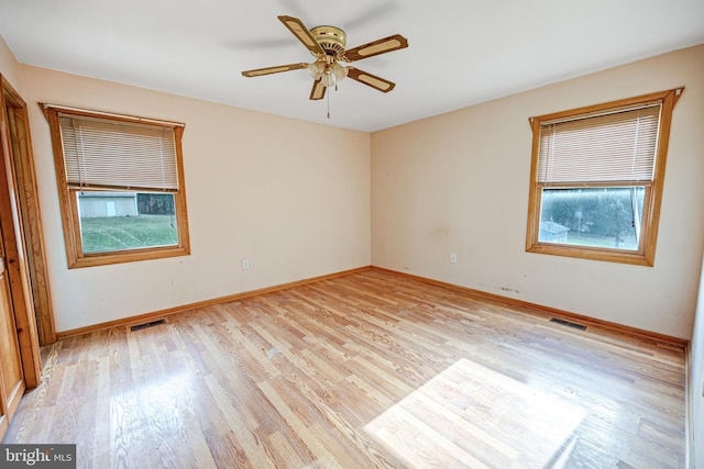 empty room featuring light wood-type flooring, plenty of natural light, and ceiling fan