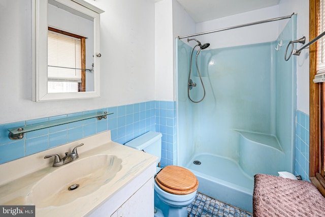 bathroom with vanity, toilet, walk in shower, and tile walls