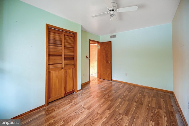 unfurnished bedroom with ceiling fan, wood-type flooring, and a closet