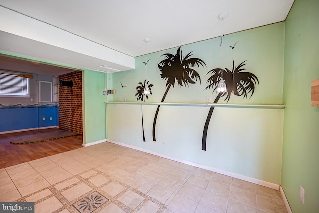 empty room with brick wall and hardwood / wood-style flooring