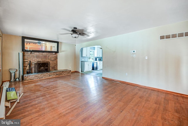 unfurnished living room with hardwood / wood-style floors, ceiling fan, and a brick fireplace