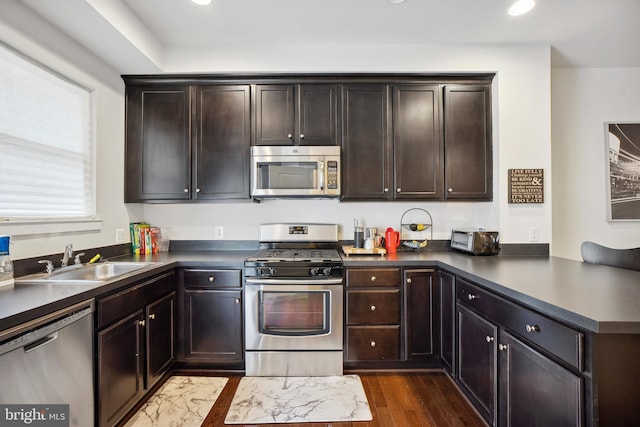 kitchen featuring dark brown cabinets, sink, stainless steel appliances, and dark wood-type flooring