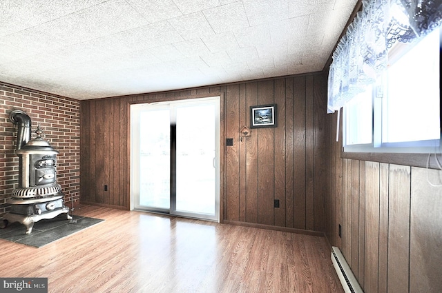 unfurnished living room with hardwood / wood-style floors, a healthy amount of sunlight, wood walls, and a wood stove