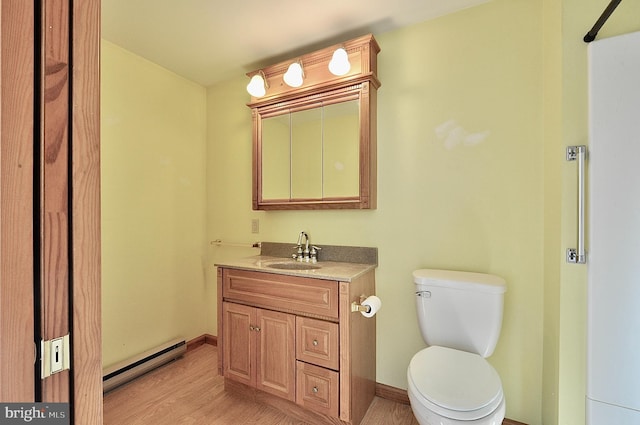 bathroom with wood-type flooring, vanity, a baseboard radiator, and toilet