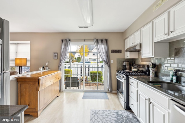 kitchen featuring white cabinetry, sink, stainless steel appliances, decorative backsplash, and light wood-type flooring