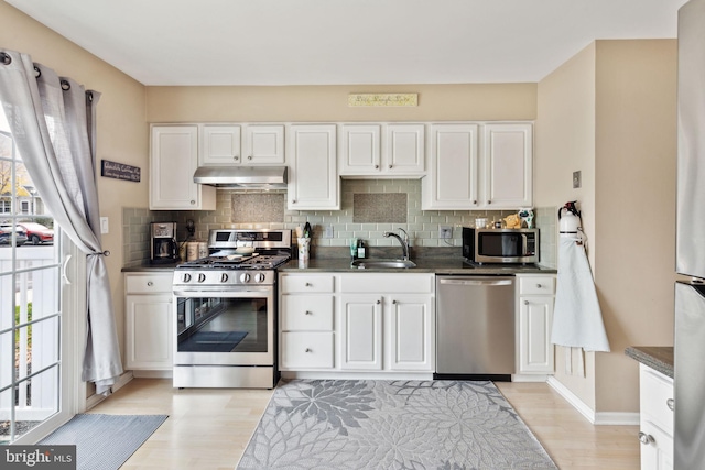 kitchen featuring decorative backsplash, white cabinetry, sink, and appliances with stainless steel finishes