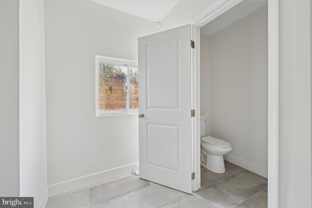 bathroom featuring tile patterned flooring, vaulted ceiling, and toilet