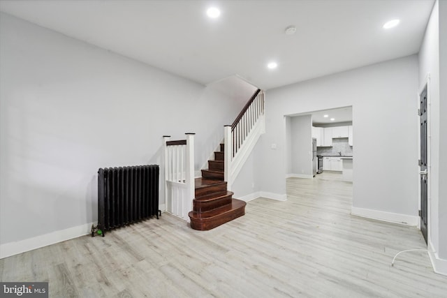 stairway featuring hardwood / wood-style floors and radiator heating unit