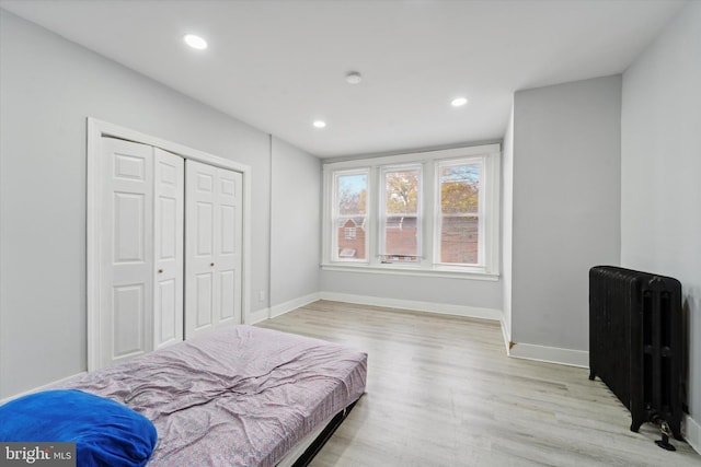 bedroom featuring light hardwood / wood-style floors, radiator, and a closet