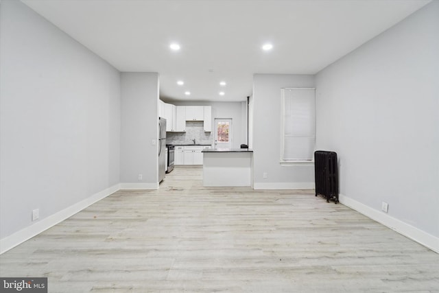 unfurnished living room featuring radiator heating unit and light hardwood / wood-style flooring