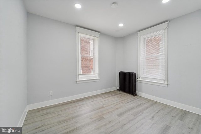 unfurnished room with radiator heating unit and light hardwood / wood-style flooring