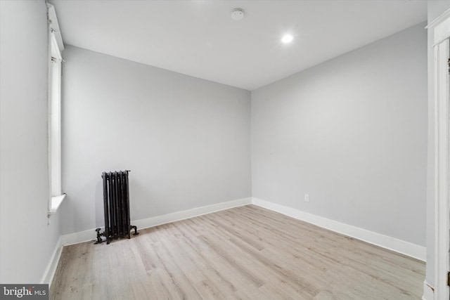 unfurnished room with radiator heating unit and light hardwood / wood-style flooring