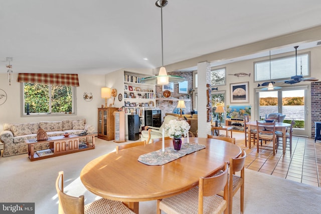 dining room featuring a wealth of natural light, a fireplace, ceiling fan, and tile patterned flooring