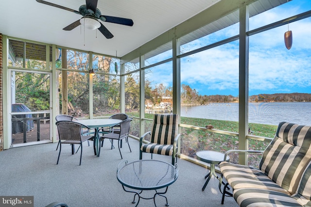 sunroom / solarium with ceiling fan and a water view