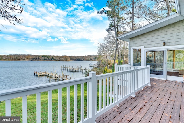 wooden deck featuring a boat dock, a water view, and a lawn