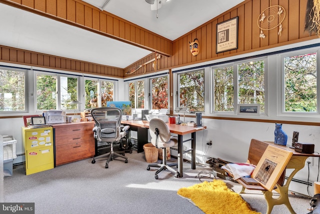 carpeted office space featuring plenty of natural light, lofted ceiling, baseboard heating, and wooden walls