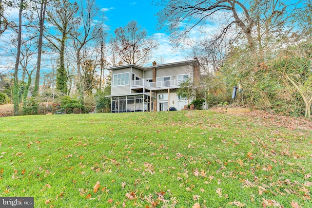 rear view of property featuring a lawn and a sunroom