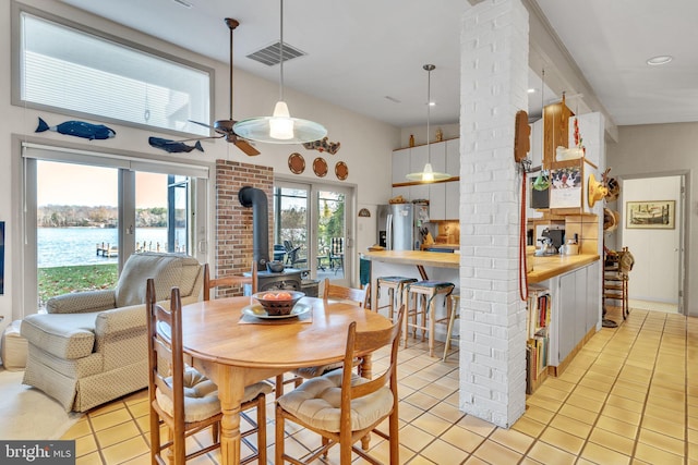 dining room with a water view, light tile patterned floors, and a wood stove