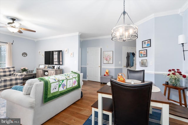 living room with ornamental molding, wood-type flooring, and ceiling fan with notable chandelier