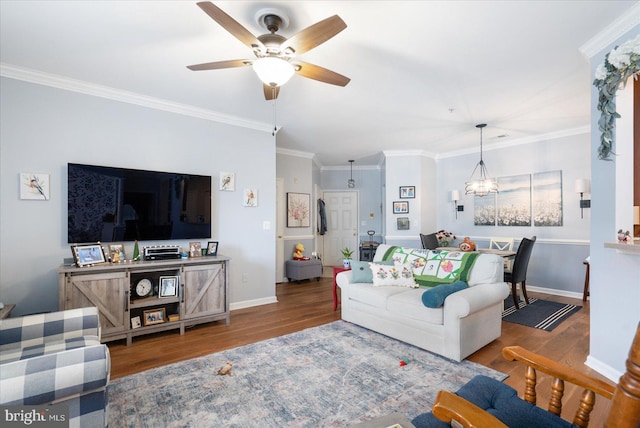 living room featuring ornamental molding, wood-type flooring, and ceiling fan with notable chandelier