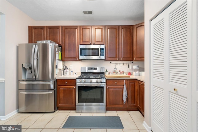 kitchen with appliances with stainless steel finishes, a textured ceiling, and light tile patterned floors