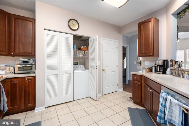 kitchen featuring washer / dryer, sink, dishwasher, and light tile patterned floors