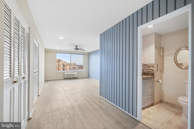 corridor with light wood-type flooring and an AC wall unit