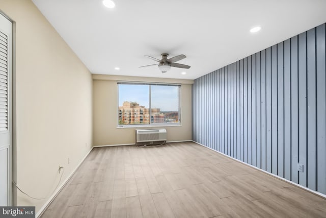 empty room featuring ceiling fan, light wood-type flooring, and a wall unit AC