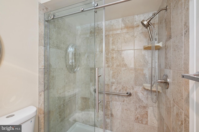 bathroom featuring toilet and a shower with shower door