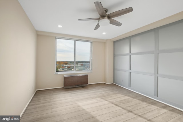 spare room featuring ceiling fan, radiator, and light hardwood / wood-style flooring