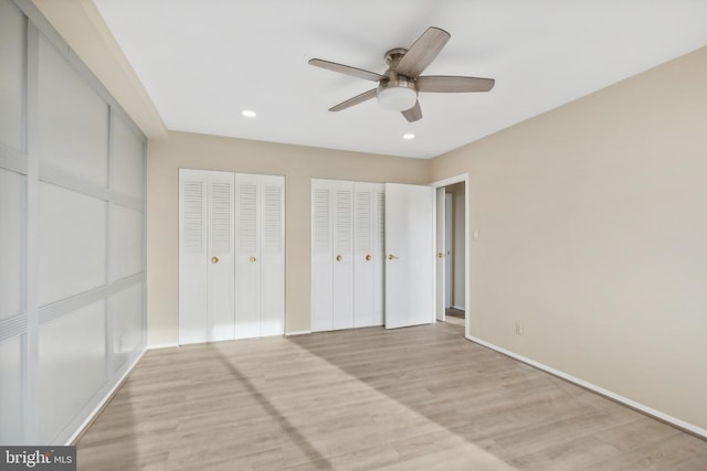 unfurnished bedroom with ceiling fan, light wood-type flooring, and two closets