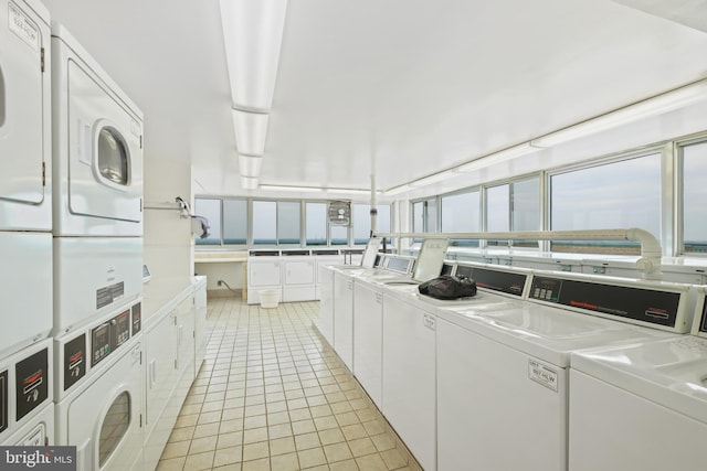 clothes washing area with separate washer and dryer, light tile patterned floors, a healthy amount of sunlight, and stacked washer / dryer