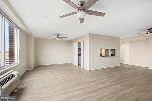 unfurnished living room with ceiling fan, light hardwood / wood-style floors, and an AC wall unit