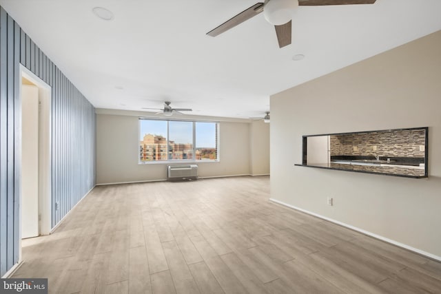 unfurnished living room featuring a wall mounted air conditioner and light wood-type flooring