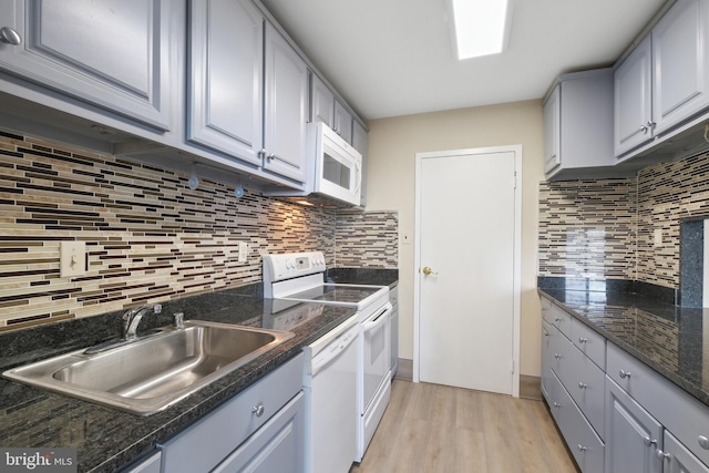 kitchen with decorative backsplash, light wood-type flooring, white appliances, and sink