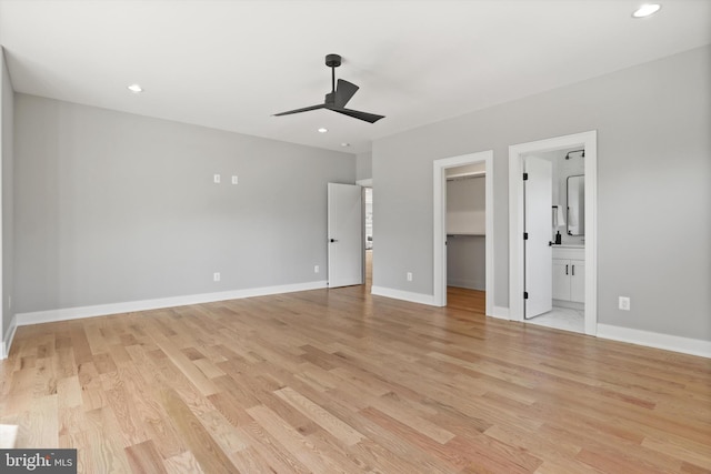 unfurnished bedroom featuring a walk in closet, ceiling fan, light hardwood / wood-style flooring, connected bathroom, and a closet