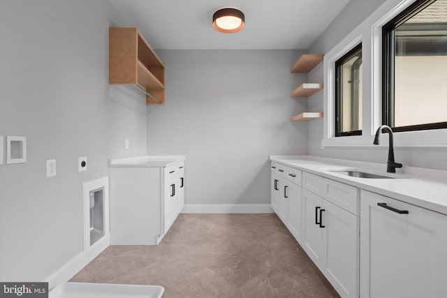 laundry room with cabinet space, baseboards, hookup for an electric dryer, and a sink