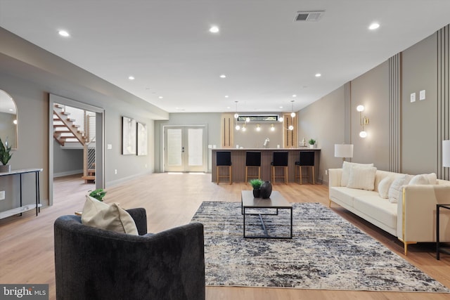 living area featuring stairway, visible vents, light wood-style flooring, recessed lighting, and french doors