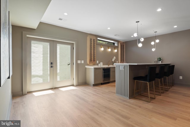 bar with visible vents, wet bar, light wood-style flooring, wine cooler, and french doors