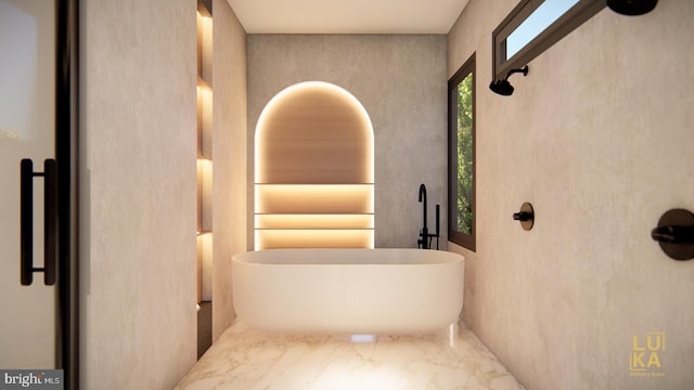 full bathroom featuring marble finish floor, a freestanding bath, and a sink