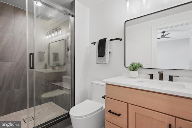 bathroom with ceiling fan, toilet, a shower with shower door, and vanity