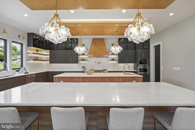 kitchen with a kitchen island with sink, ventilation hood, oven, decorative backsplash, and open shelves