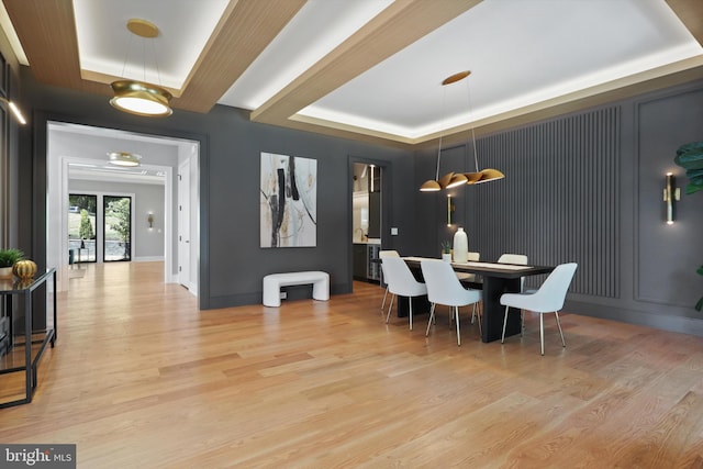 dining room with light hardwood / wood-style floors and a tray ceiling