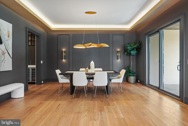 dining room with light wood-type flooring and a raised ceiling