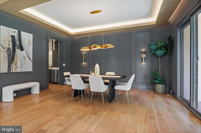 dining space featuring a tray ceiling and light hardwood / wood-style flooring