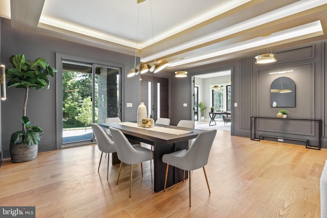 dining area featuring light wood-type flooring and a raised ceiling