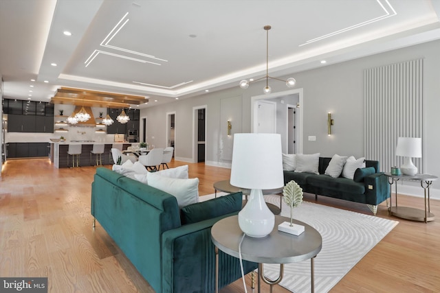 living area featuring recessed lighting, a raised ceiling, and light wood finished floors